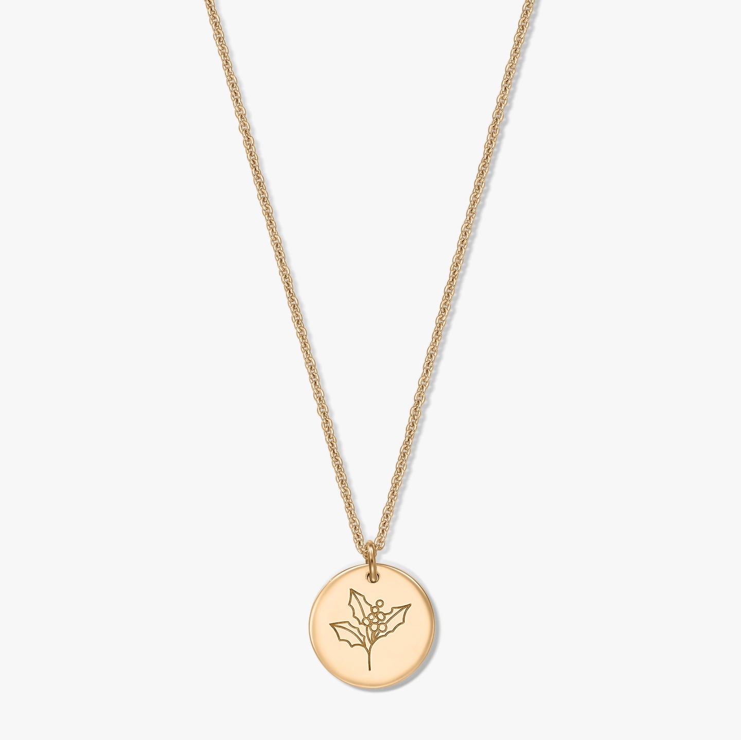 Collier en argent sterling plaqué or avec pendentif disque rond gravé d’un motif de houx (fleur de naissance de décembre), sur fond blanc.