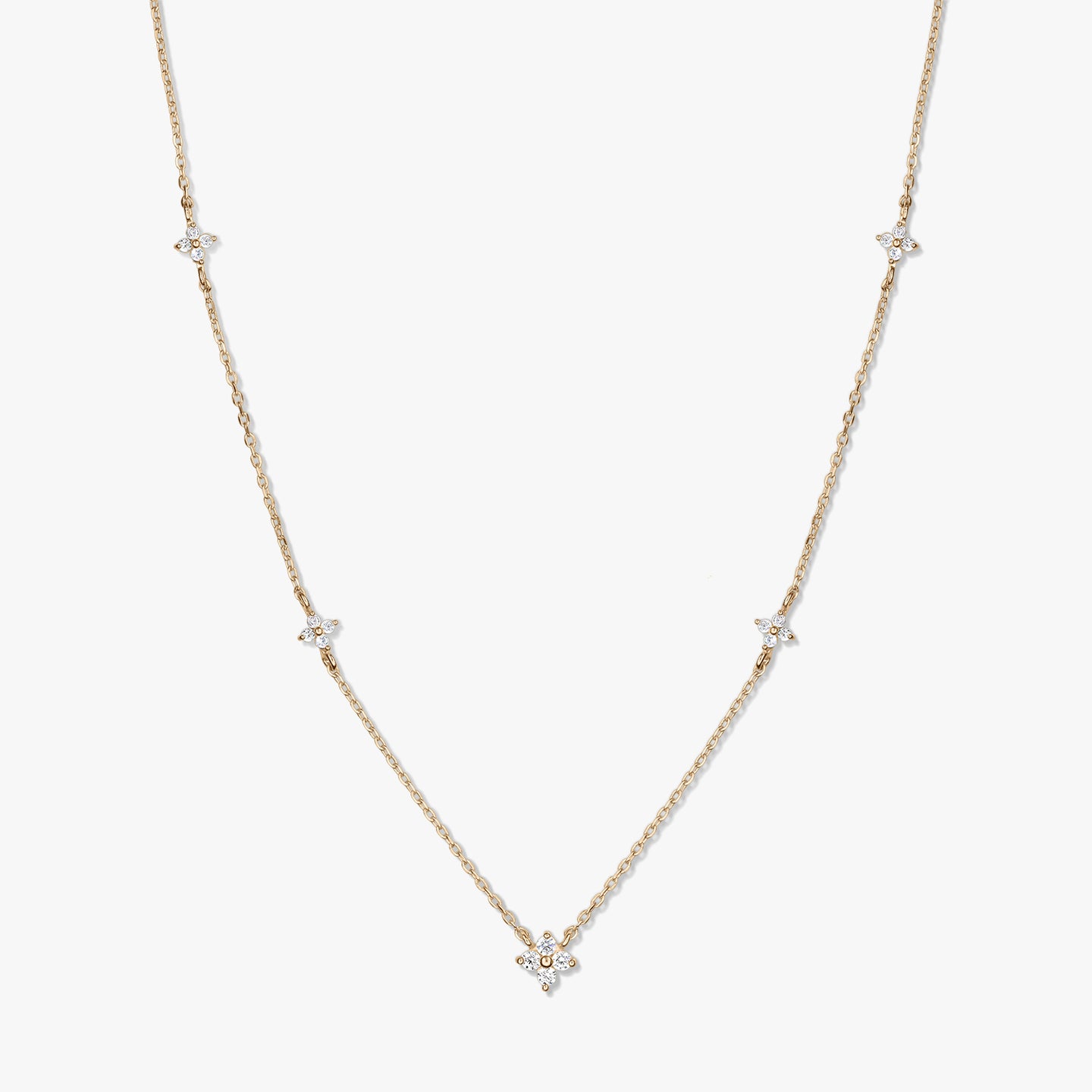 Delicate 14K yellow gold station necklace featuring small white zirconia clover motifs on a fine chain, photographed against a white background.