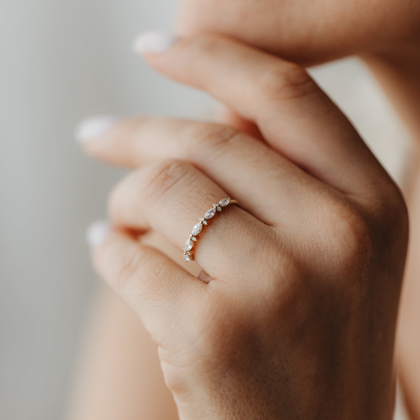Close-up of a hand wearing the Fiorelle yellow gold diamond ring featuring alternating marquise and round-cut stones.
