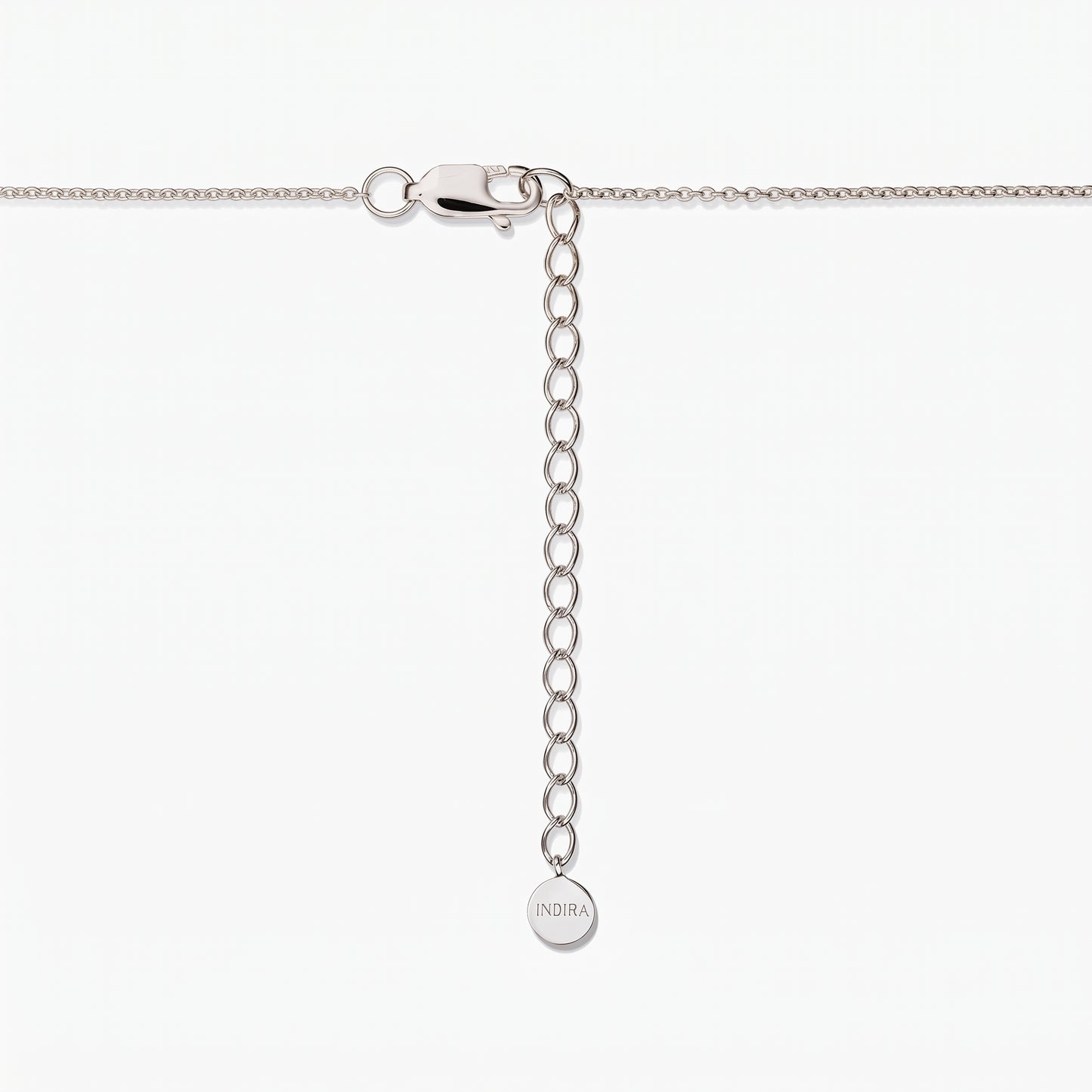 Close-up of a sterling silver necklace clasp with adjustable extender chain and a small round Indira tag on a white background.