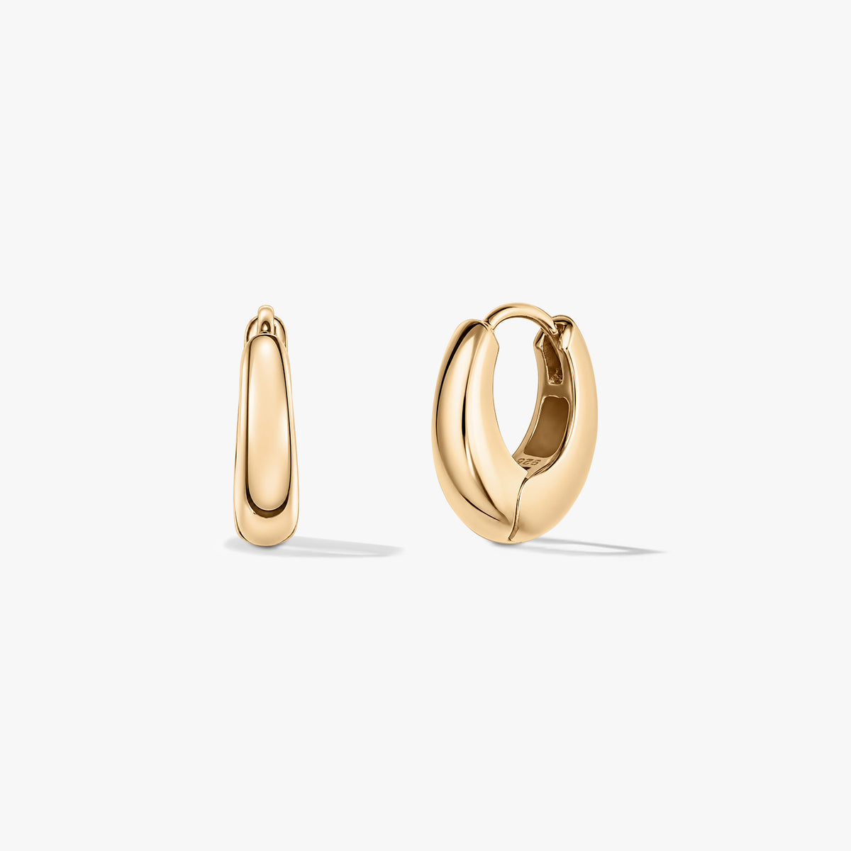Pair of small gold mini dome huggie hoop earrings on a white background.