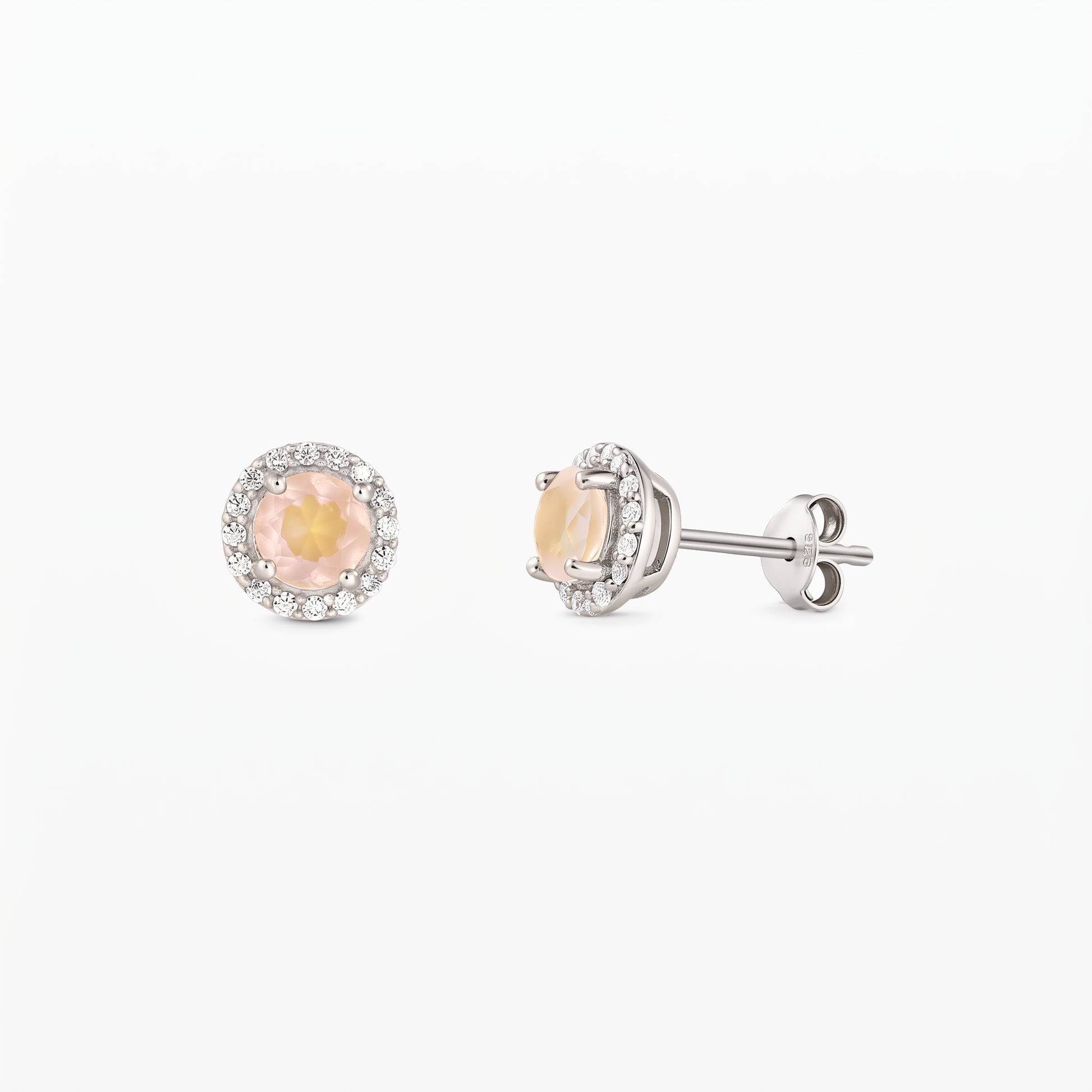 Paire de puces d’oreilles en argent sterling, chacune ornée d’un quartz rose rond au centre et d’un halo de zirconia, vues de face et de profil sur fond blanc.