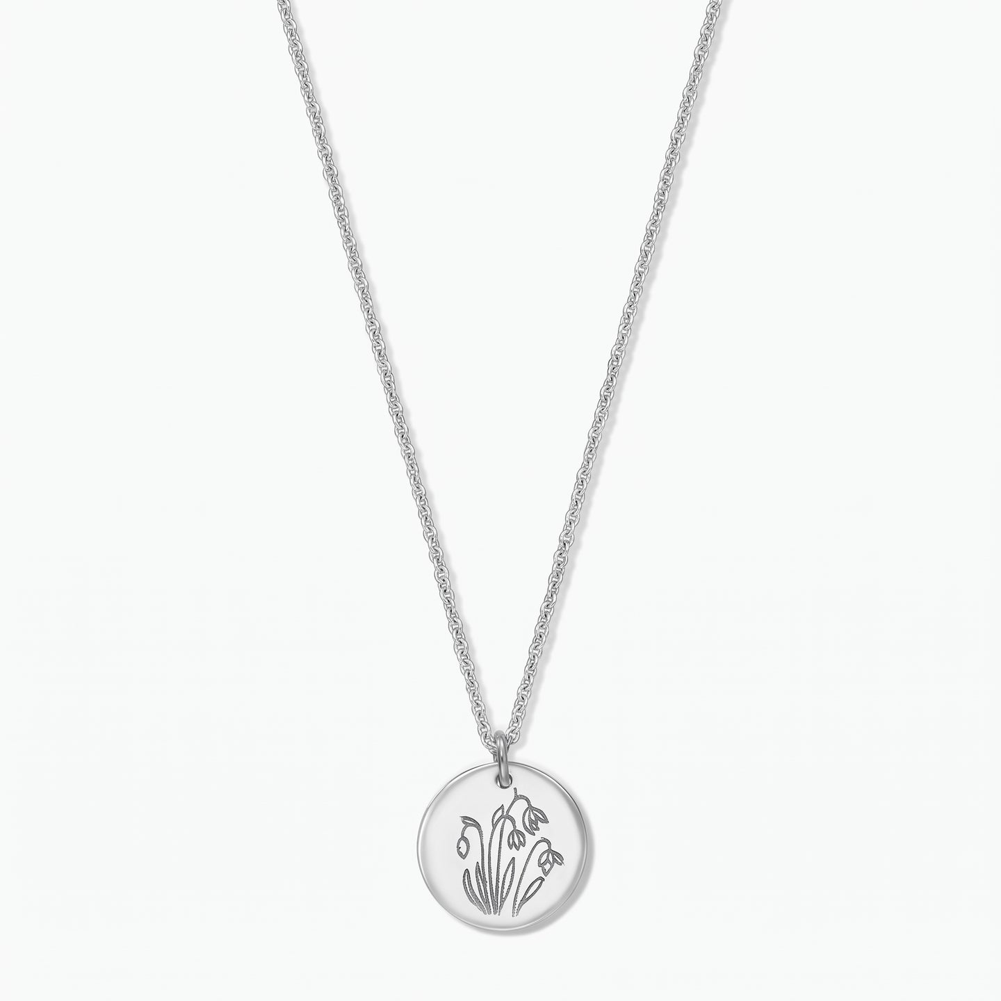 Collier fleur de naissance en argent sterling avec un pendentif disque rond gravé de perce-neige de janvier sur une chaîne fine, isolé sur fond blanc.
