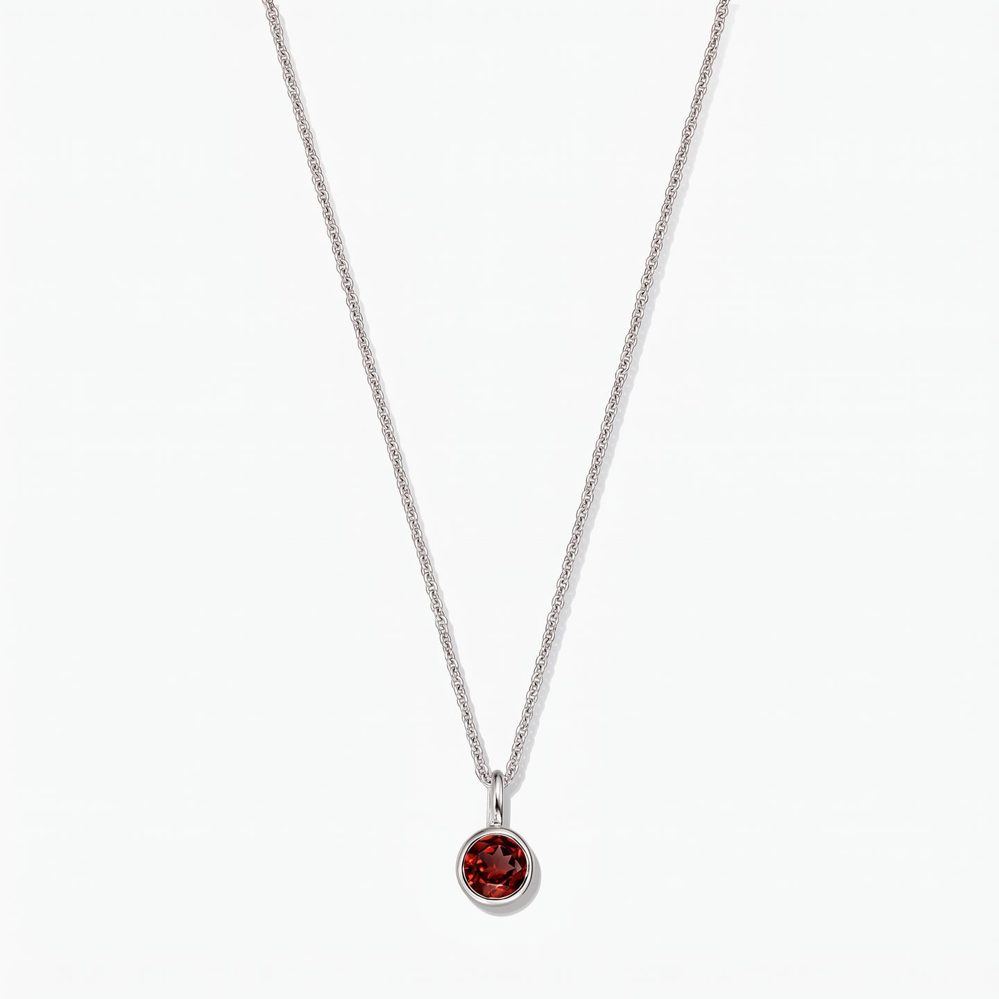 Sterling silver birthstone necklace featuring a round bezel-set garnet pendant on a white background.