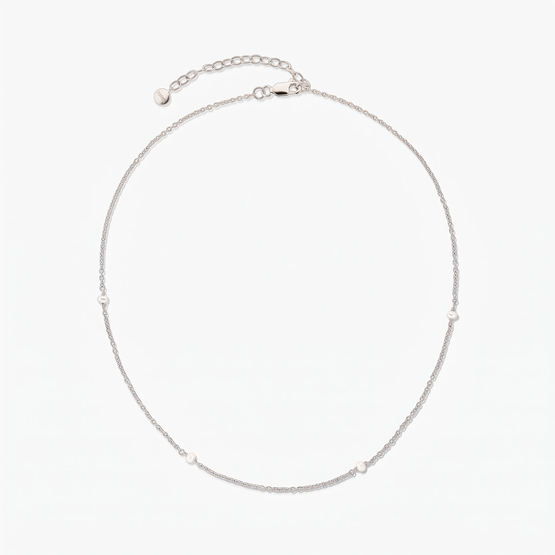 Collier chaîne en argent délicat avec de petites perles blanches espacées, présenté en cercle sur fond blanc avec une rallonge ajustable et un fermoir mousqueton.