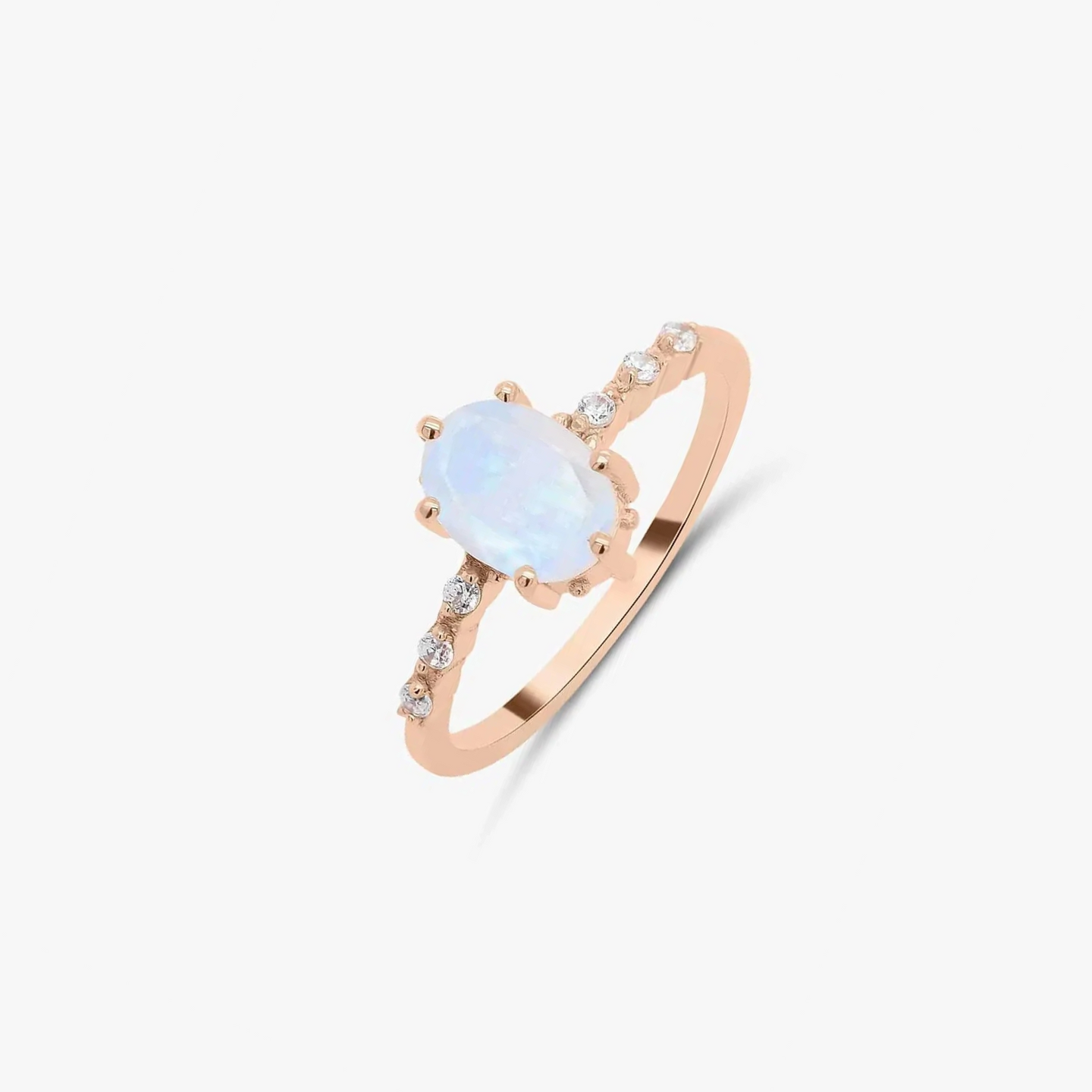 Bague en or rose avec pierre de lune et ornements de zircon sur fond blanc uni.