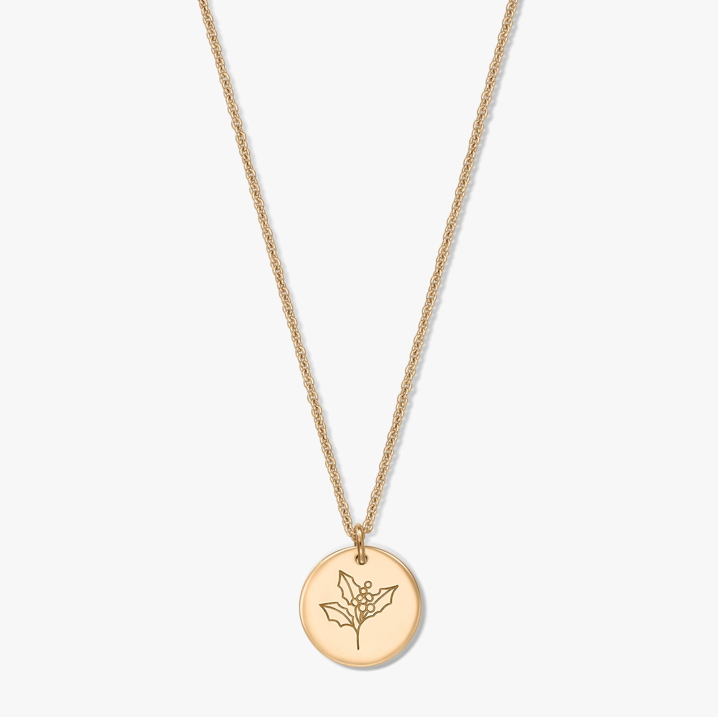 Collier en argent sterling plaqué or avec pendentif disque rond gravé d’un motif de houx (fleur de naissance de décembre), sur fond blanc.