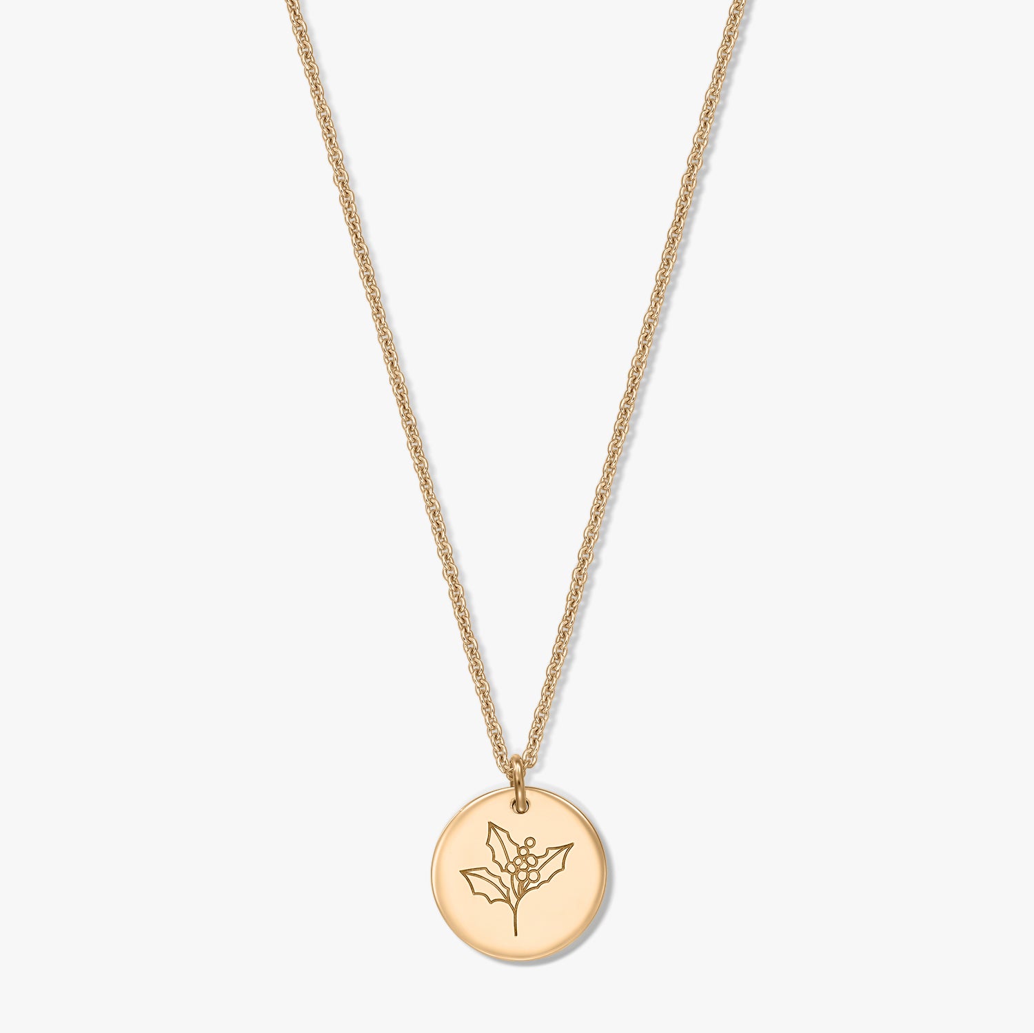 Collier en argent sterling plaqué or avec pendentif disque rond gravé d’un motif de houx (fleur de naissance de décembre), sur fond blanc.
