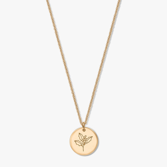 Collier en argent sterling plaqué or avec pendentif disque rond gravé d’un motif de houx (fleur de naissance de décembre), sur fond blanc.
