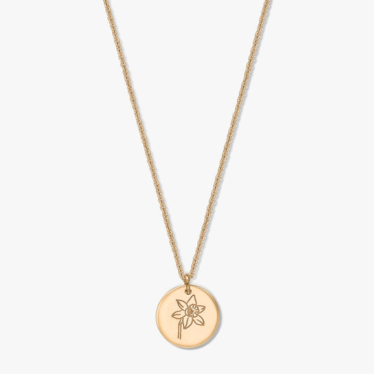 Collier en argent plaqué or avec pendentif disque rond gravé d’une jonquille de mars, photographié sur fond blanc.