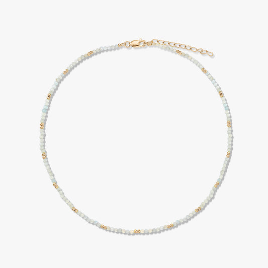 Delicate beaded moonstone necklace featuring small gold spacer beads and a gold‑plated sterling silver lobster clasp and extender, arranged in a circle on a white background.
