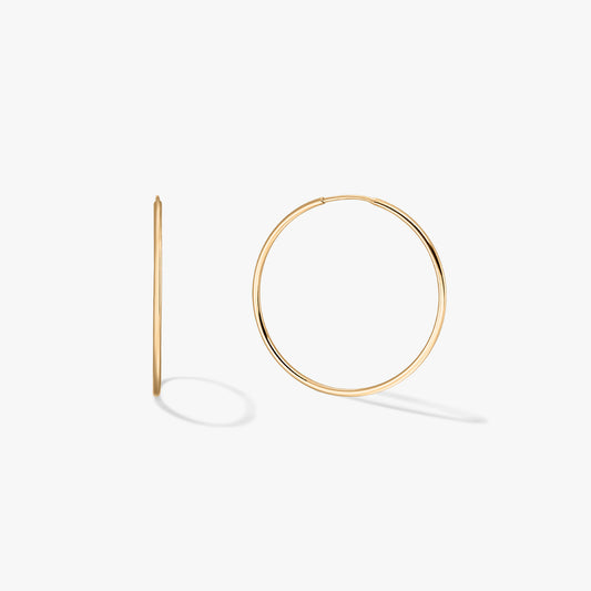 Egy pár arany karika fülbevaló fehér háttéren.