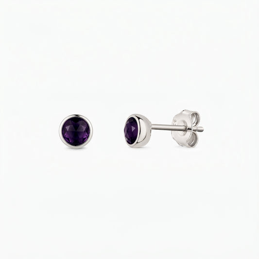 Paire de boucles d’oreilles puces en argent sterling avec pierres d’améthyste rondes facettées, serti clos, vues de face et de profil sur fond blanc.