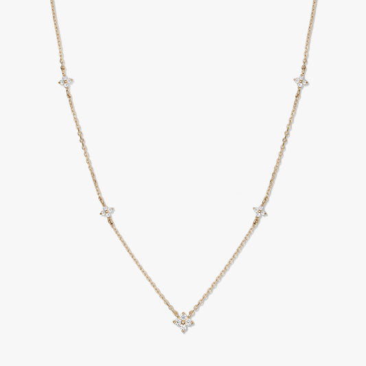 Delicate 14K yellow gold station necklace featuring small white zirconia clover motifs on a fine chain, photographed against a white background.