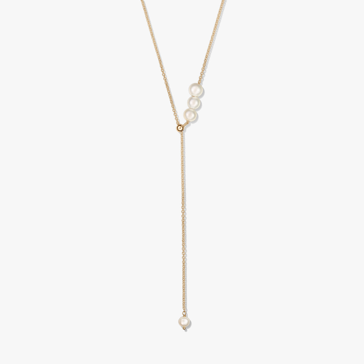 Collier lariat délicat en argent sterling plaqué or, avec un trio de perles de culture au curseur et une perle pendante unique, sur fond blanc.