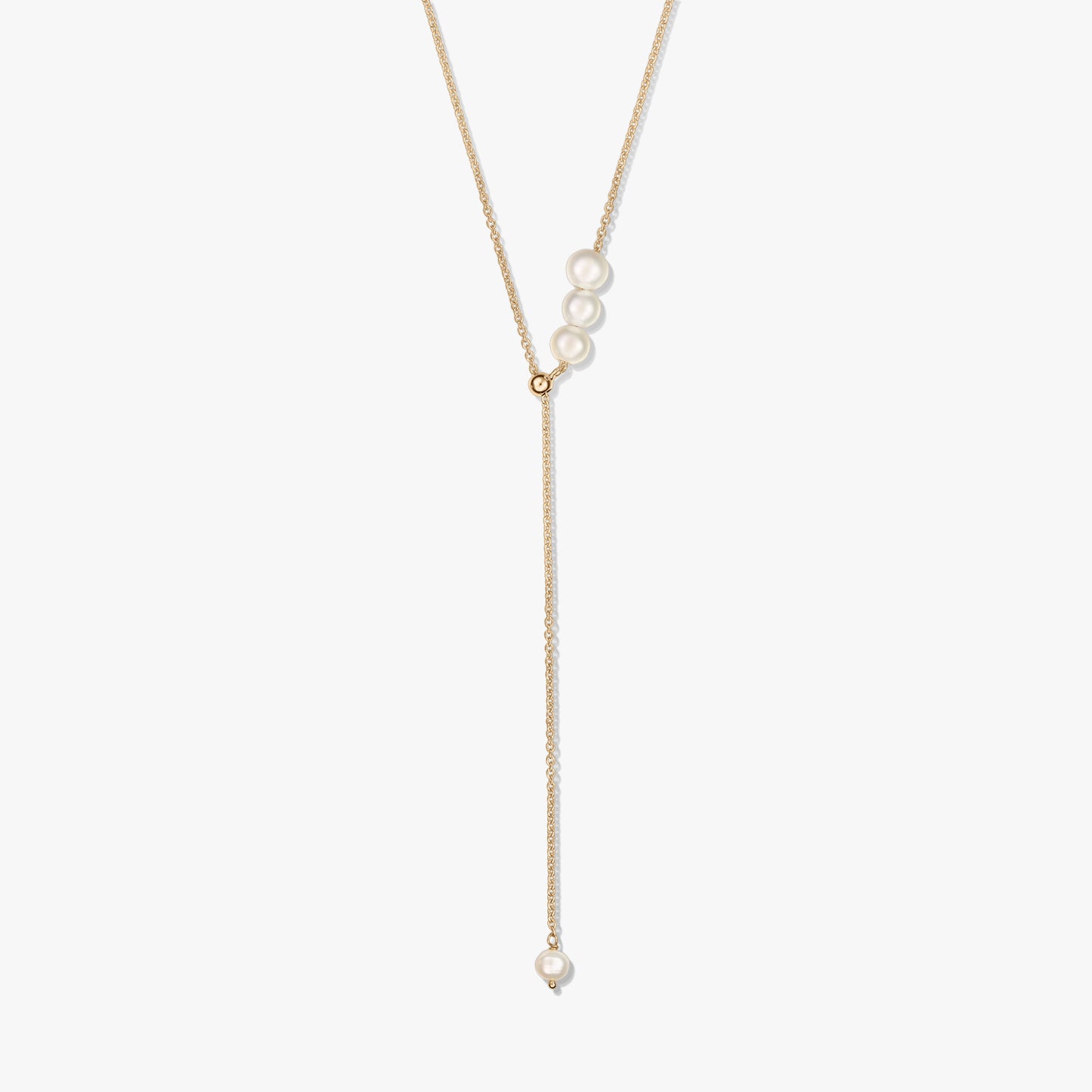 Collier lariat délicat en argent sterling plaqué or, avec un trio de perles de culture au curseur et une perle pendante unique, sur fond blanc.