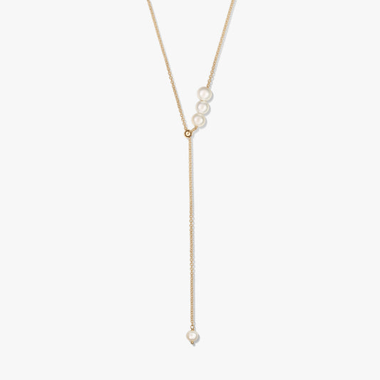 Delicate gold-plated sterling silver lariat necklace featuring a trio of cultured pearls at the slider and a single pearl drop, isolated on white.