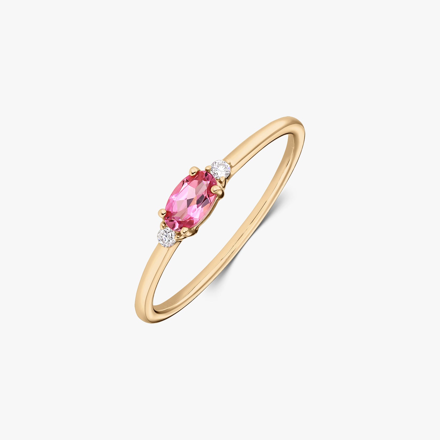 Elegáns 14K sárga arany gyűrű ovális rózsaszín turmalin központi kővel, két apró kerek gyémánttal, vékony pánton, fehér háttéren.