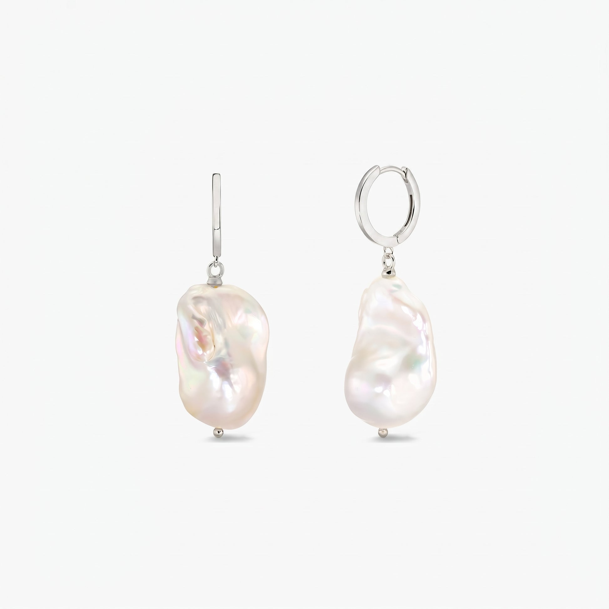 Paire de créoles en argent sterling avec de grandes perles baroques blanches, irrégulières, sur fond blanc uni.