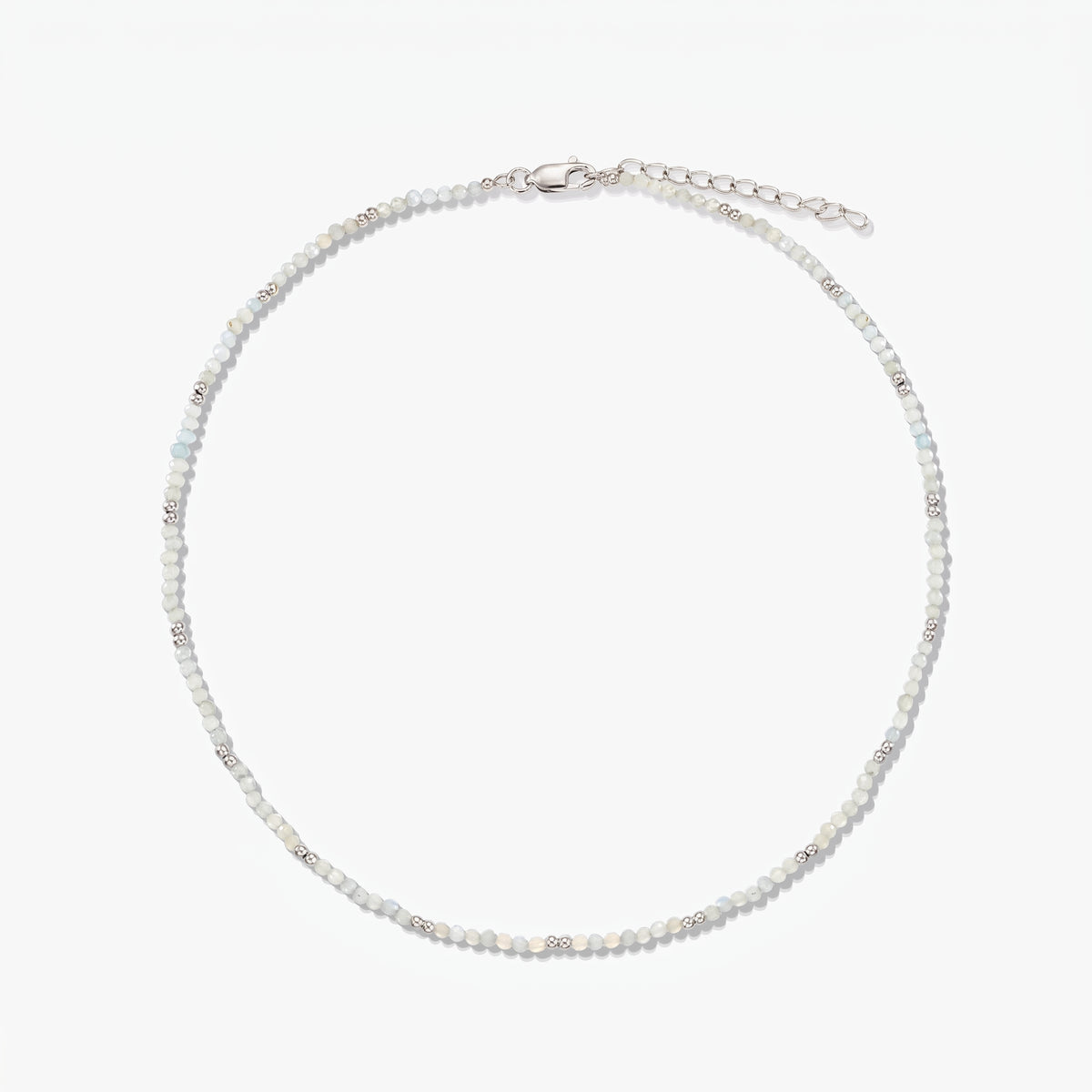 Delicate sterling silver necklace with small moonstone beads and an adjustable extender chain, photographed on a white background.