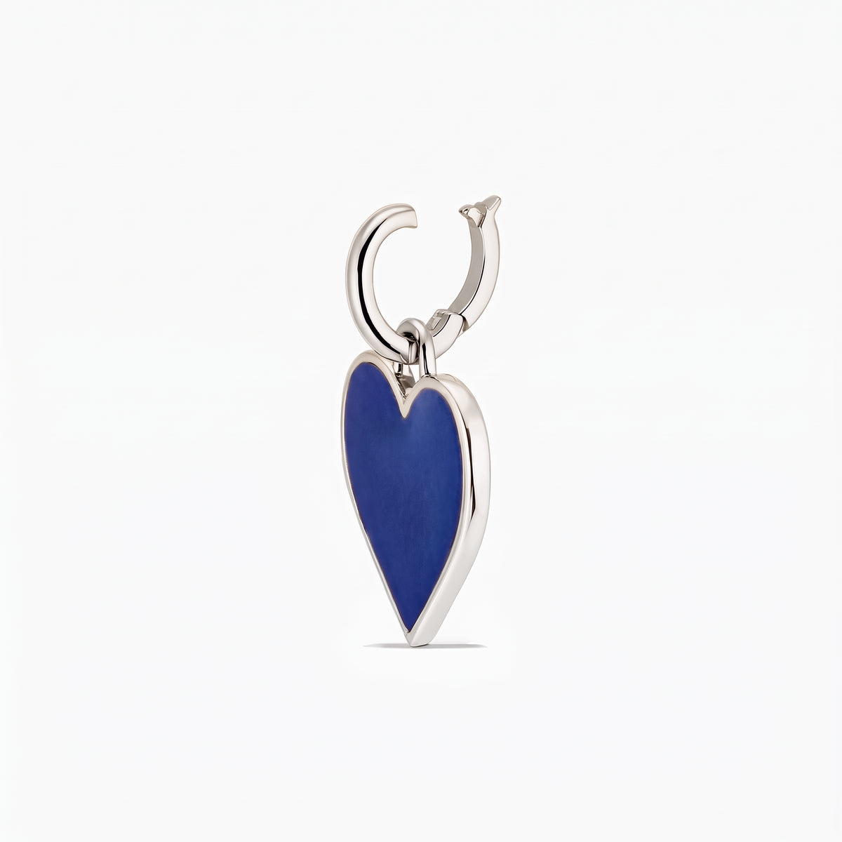 Gros plan sur un pendentif en forme de cœur en argent avec un incrusté bleu profond sur fond blanc.