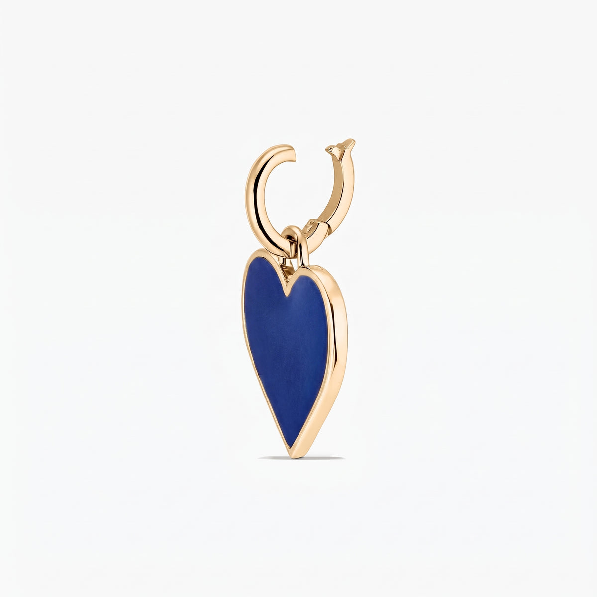 Gros plan d'un pendentif en argent avec un charm en forme de cœur bleu profond encadré d'un bord doré, isolé sur fond blanc.
