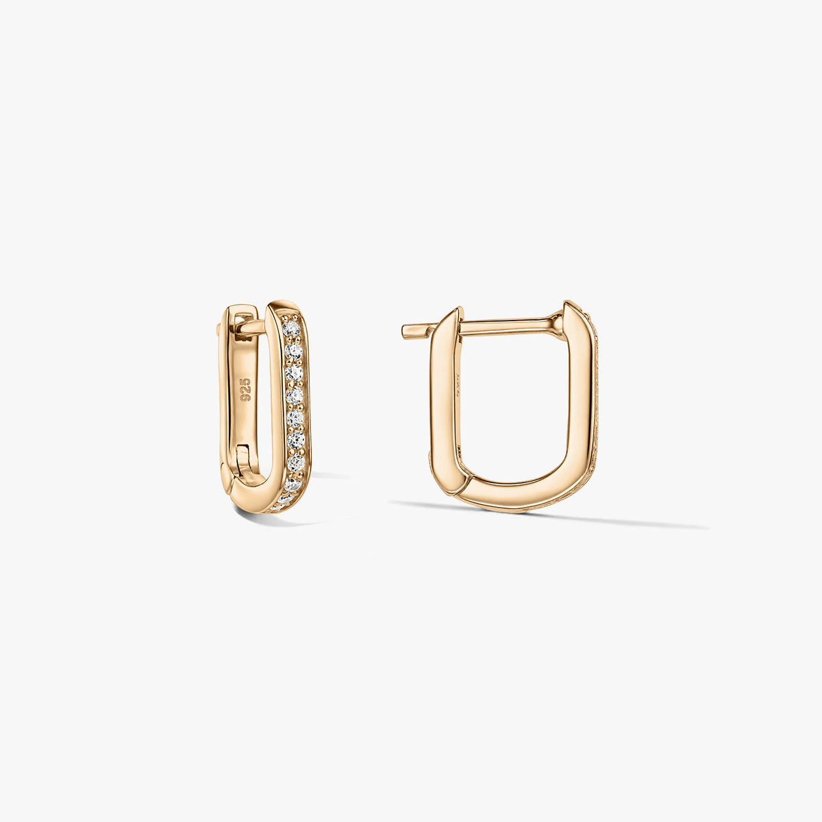 Paire de boucles d'oreilles créoles huggy en forme de U de couleur or en argent 925 avec zirconias clairs pavés, présentées sur un fond blanc avec une boucle ouverte et l'autre fermée.