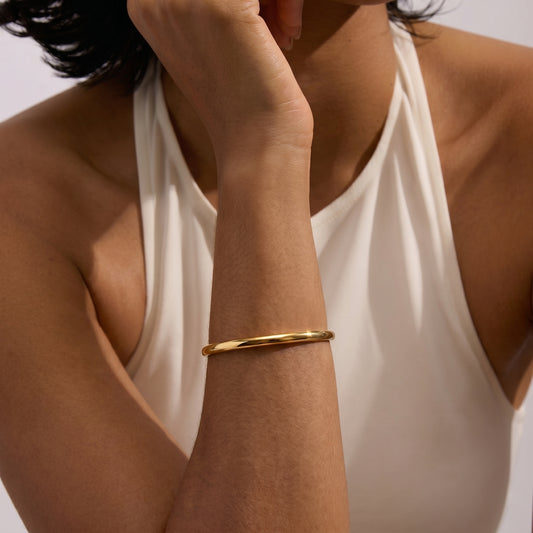 Gros plan d'une personne portant un bracelet Serena doré argenté au poignet sur un fond clair.