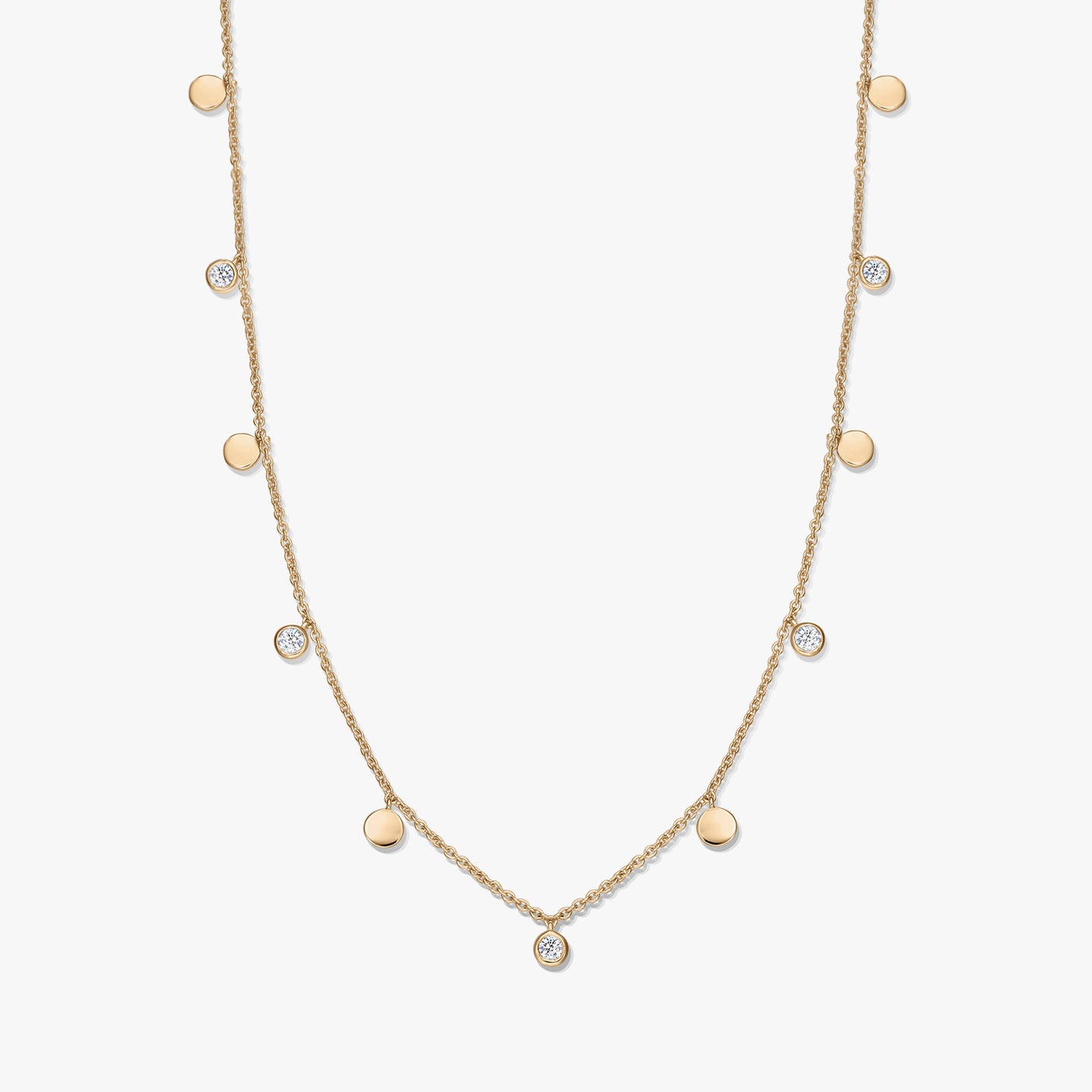 Collier à stations en argent sterling plaqué or avec de petits disques polis alternés et des topazes blanches en serti clos sur une chaîne délicate, photographié sur fond blanc.
