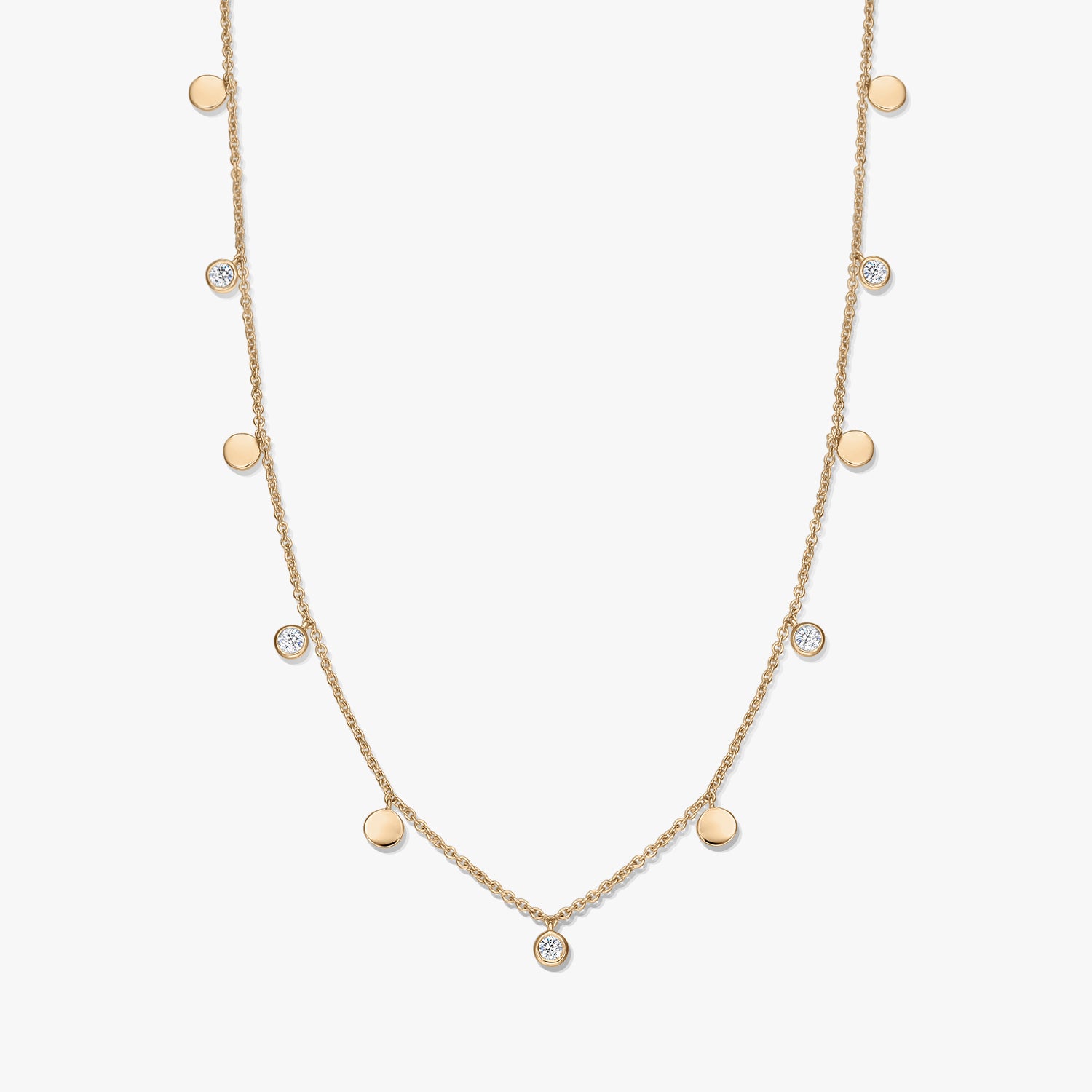 Collier à stations en argent sterling plaqué or avec de petits disques polis alternés et des topazes blanches en serti clos sur une chaîne délicate, photographié sur fond blanc.