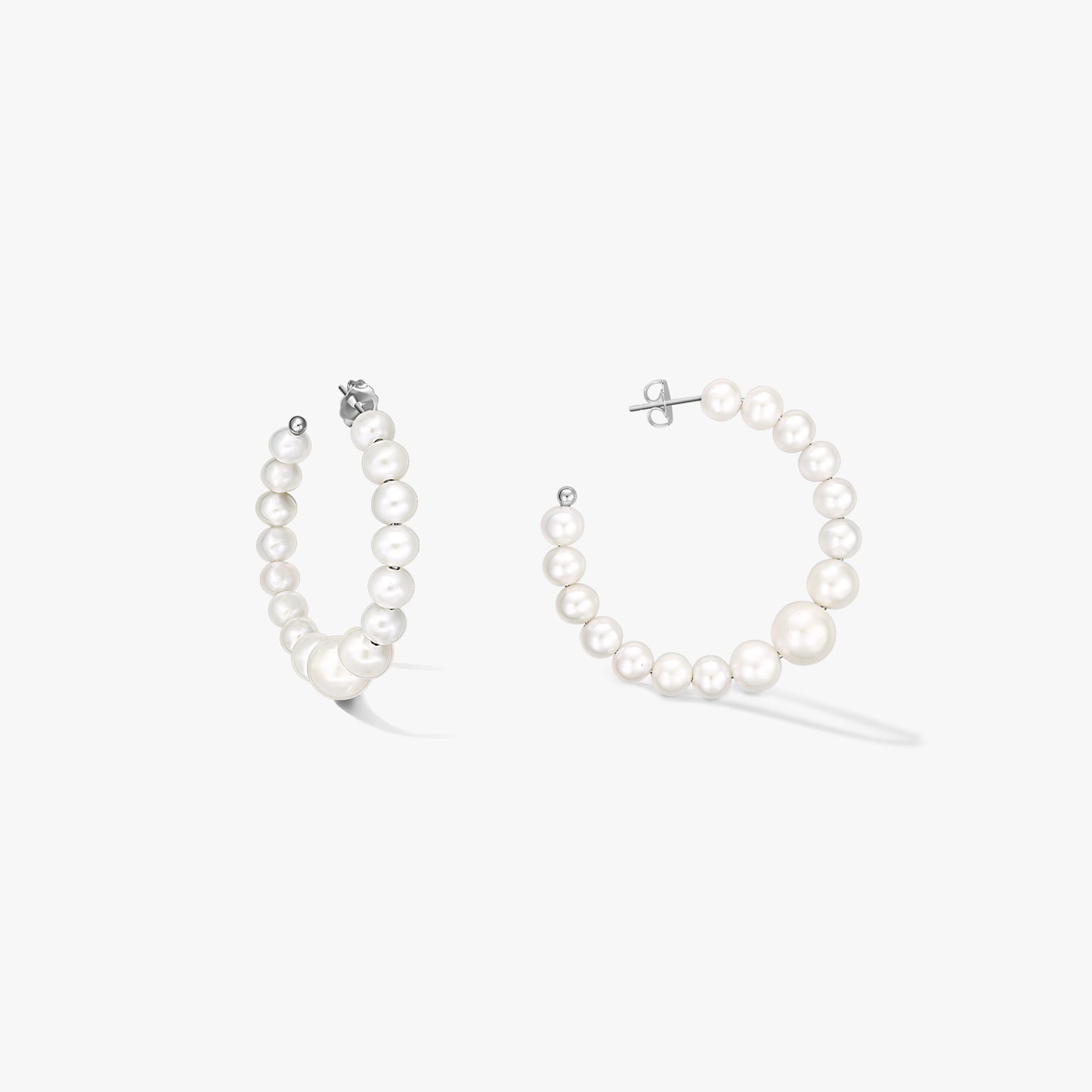 Pair of sterling-silver hoop earrings strung with graduated natural white pearls, shown on a white background.