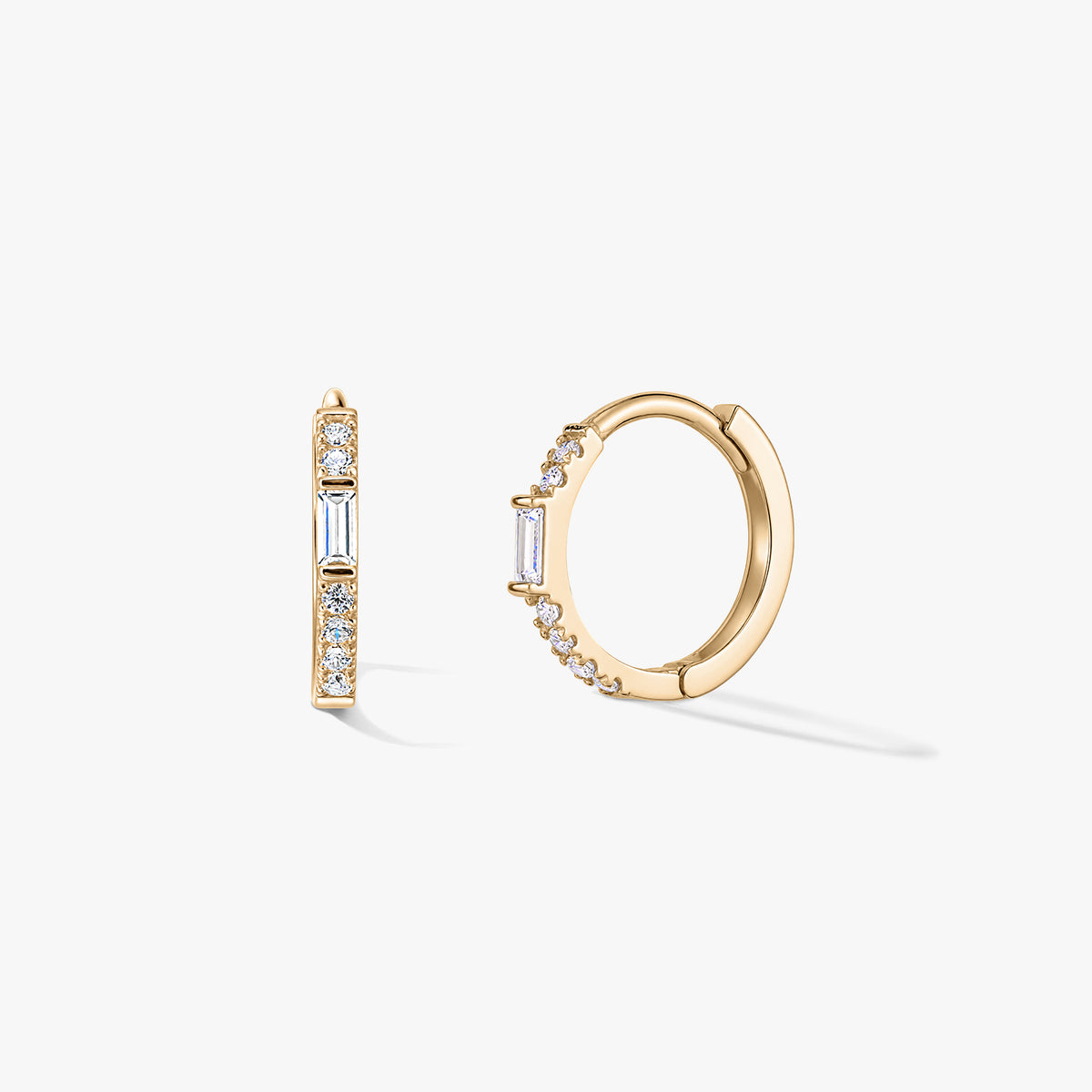 Paire de boucles d'oreilles créoles huggie en or avec pavé de zircones claires et un accent vertical baguette, présentée sur un fond blanc.