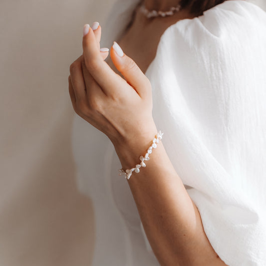 Close-up of a wrist wearing a delicate Keshi pearl bracelet in sterling silver, photographed in soft natural light against a white blouse.