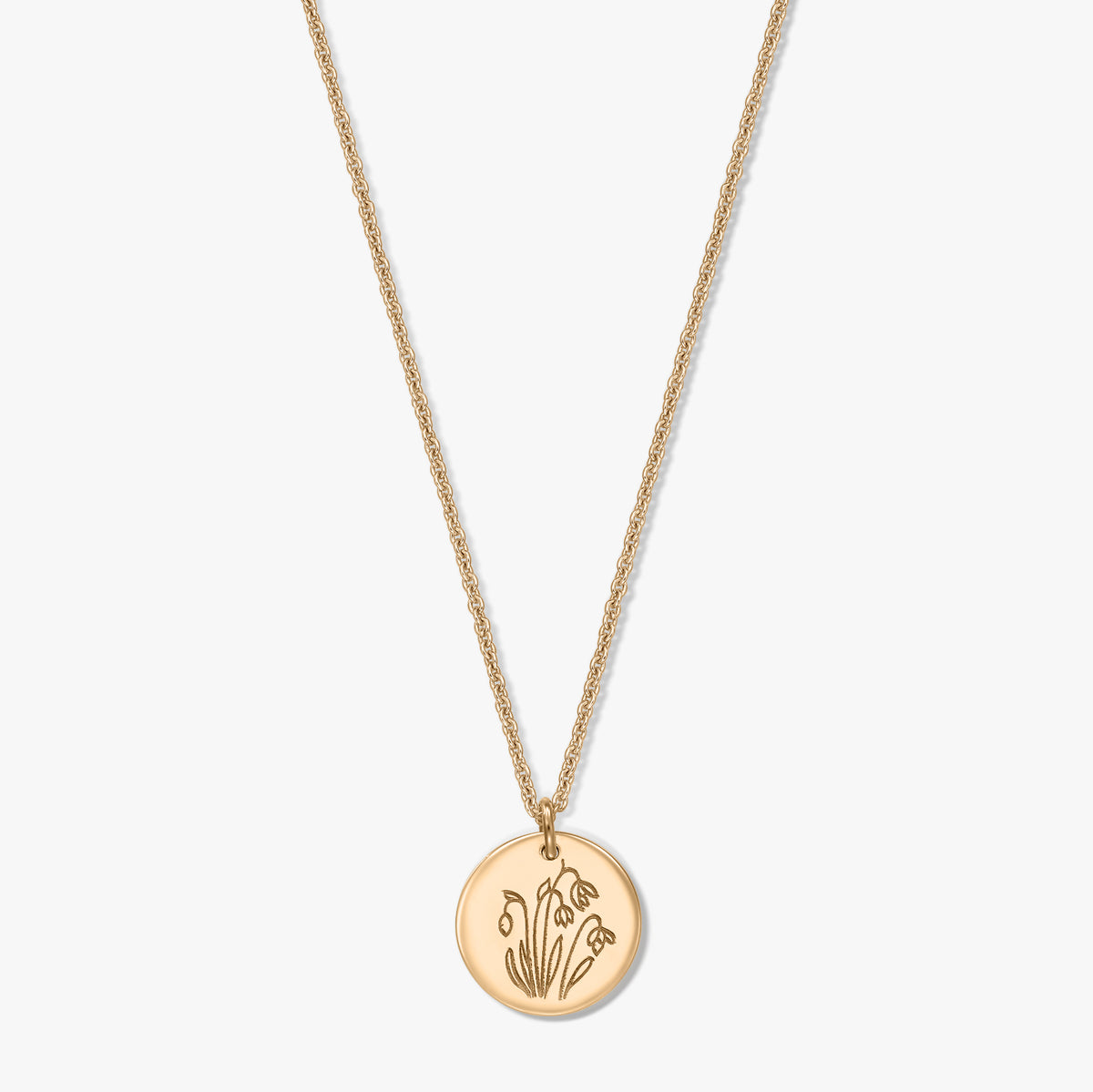 Collier en argent sterling plaqué or avec un pendentif disque rond gravé du perce-neige, fleur de naissance de janvier, présenté sur fond blanc.