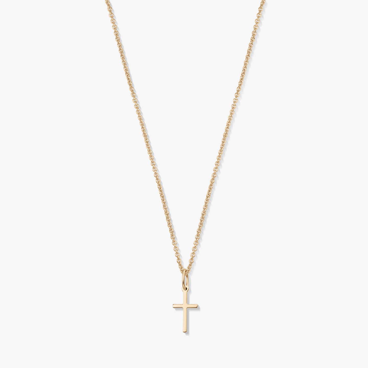 Minimalist 14K yellow gold necklace with a small cross pendant on a fine chain, isolated on a white background.