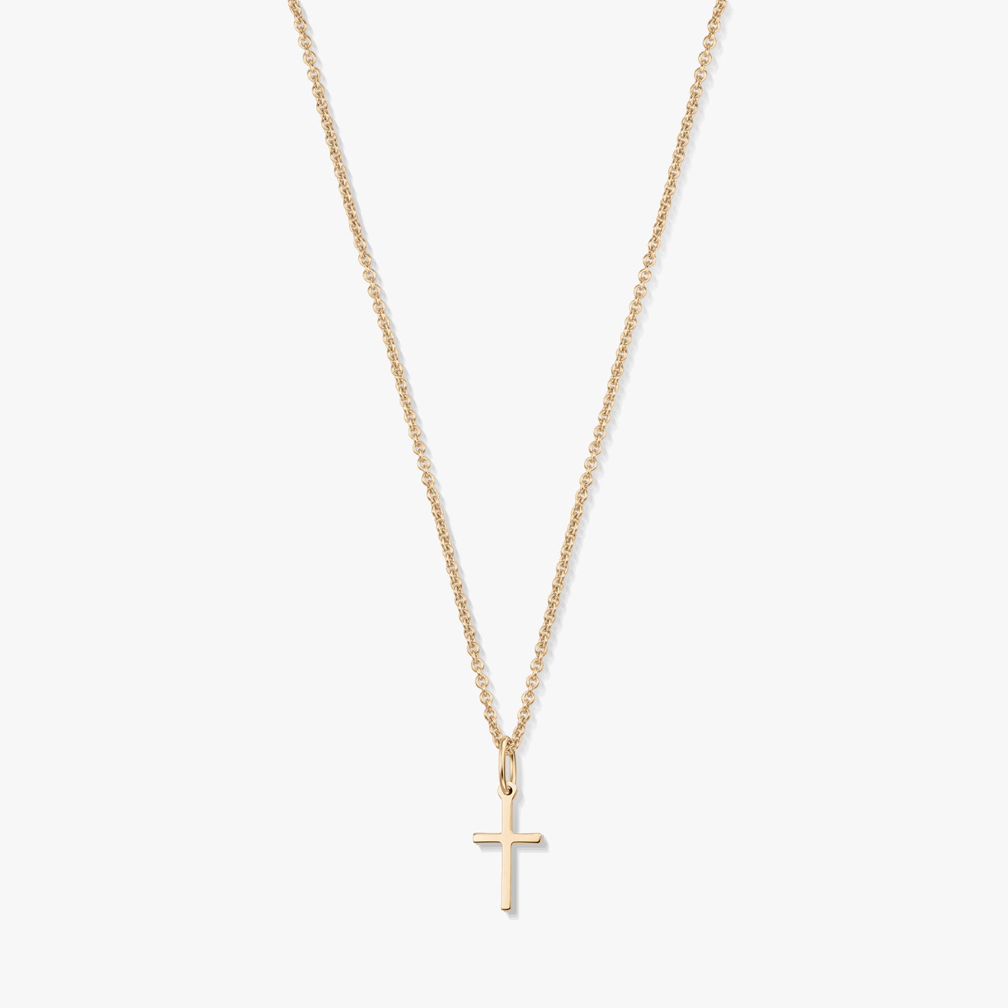 Minimalist 14K yellow gold necklace with a small cross pendant on a fine chain, isolated on a white background.
