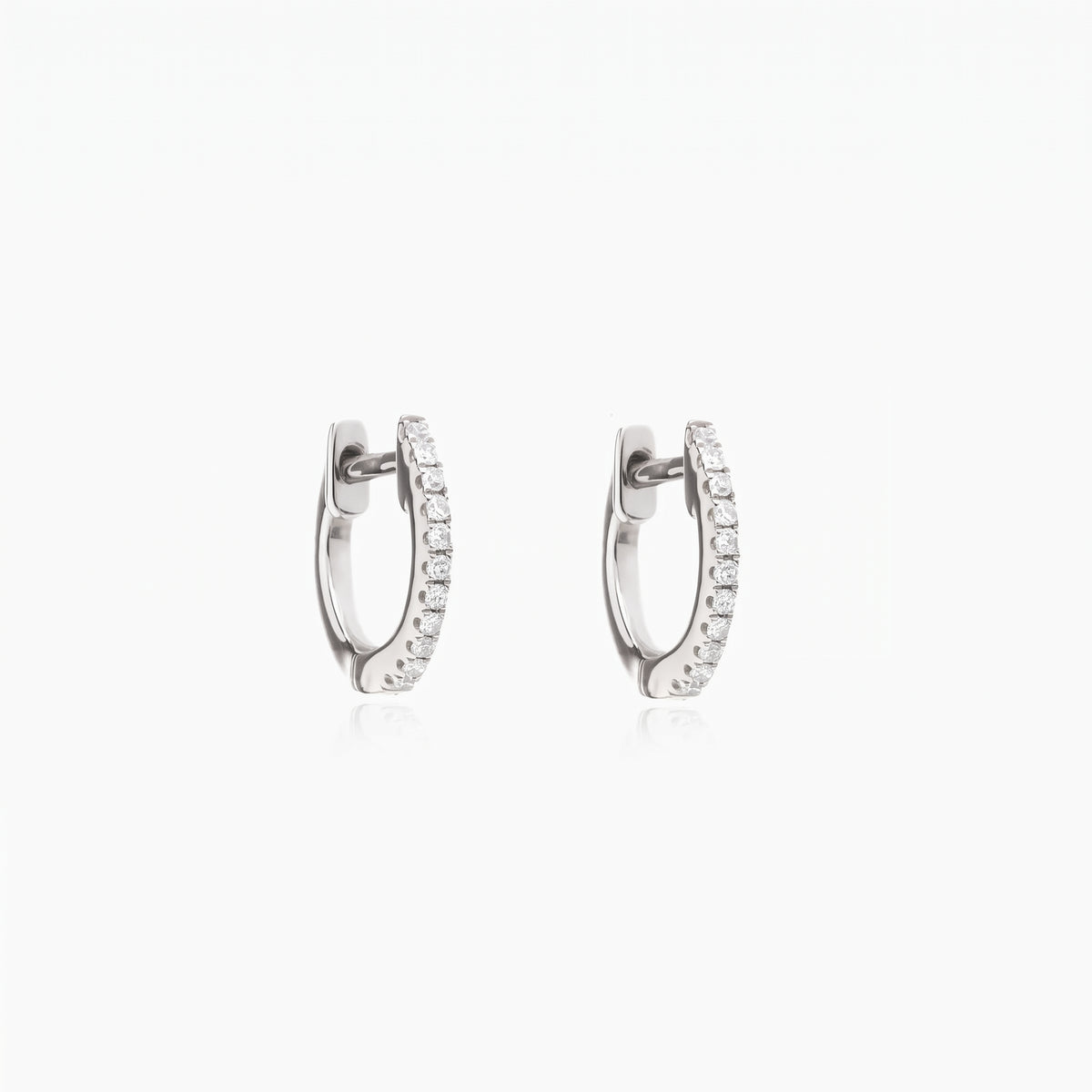 Pair of Sadie silver huggie hoop earrings with clear pavé zirconia on a white background.