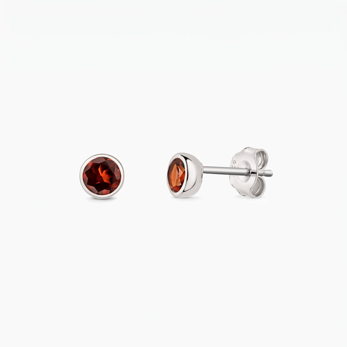 Pair of sterling silver stud earrings featuring round garnet gemstones, shown from the front and side on a white background, with butterfly backs visible.