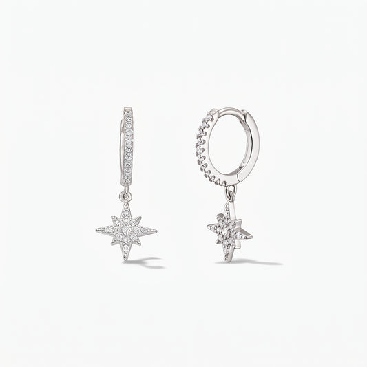 Pair of 925 sterling silver huggie hoop earrings with pavé white zirconia North Star charms on a white background.