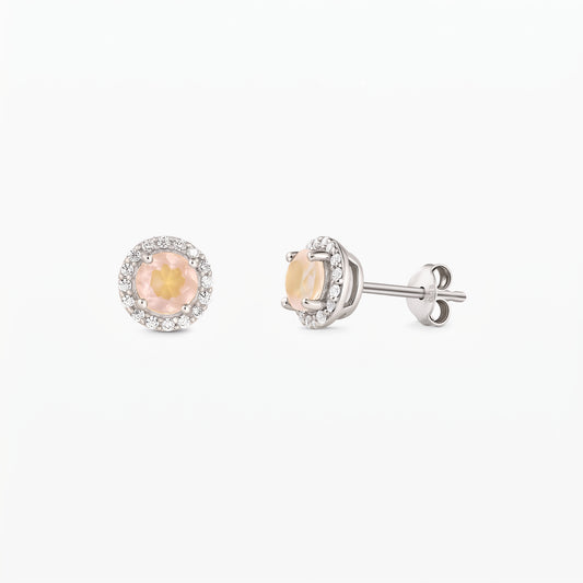 Paire de puces d’oreilles en argent sterling, chacune ornée d’un quartz rose rond au centre et d’un halo de zirconia, vues de face et de profil sur fond blanc.