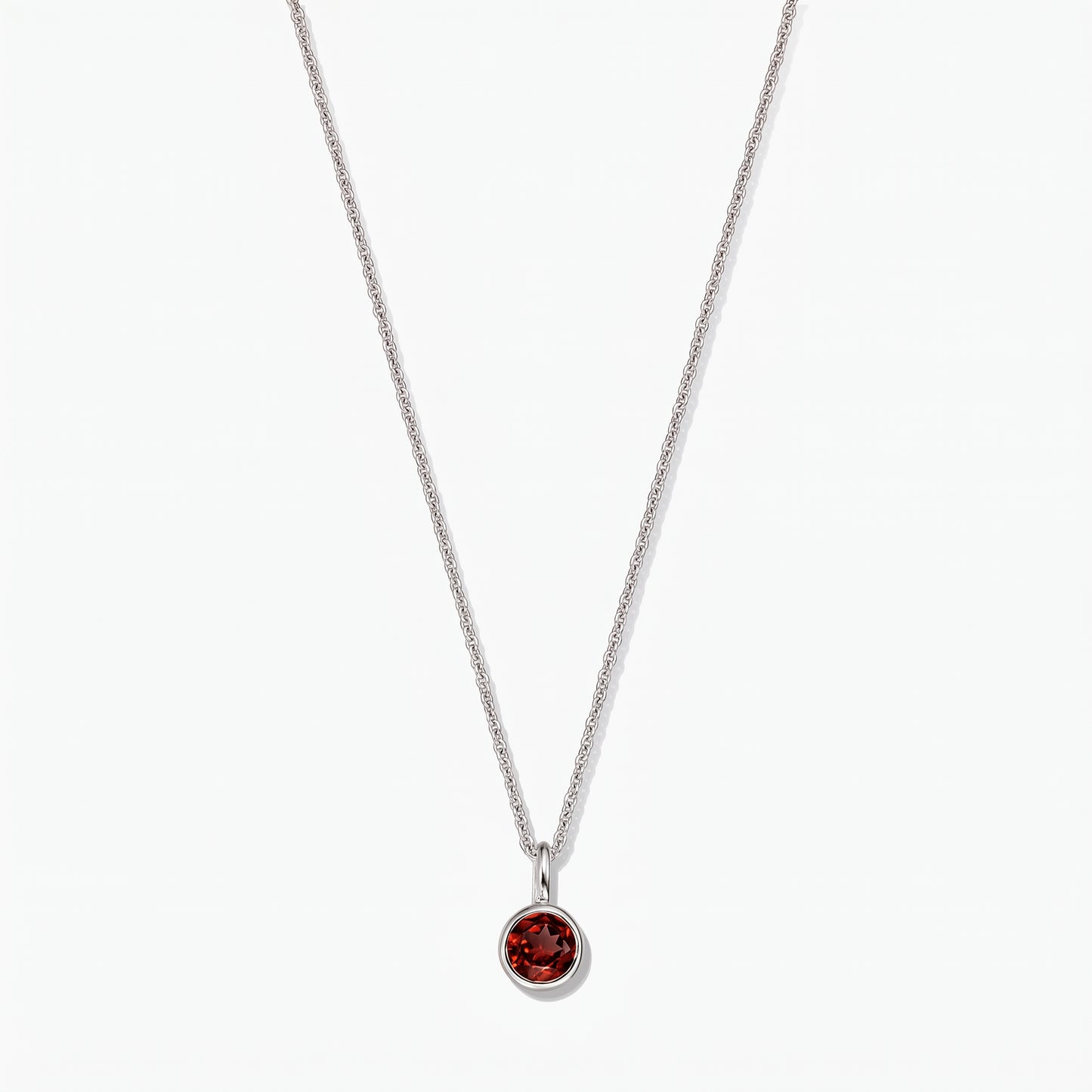 Sterling silver birthstone necklace featuring a round bezel-set garnet pendant on a white background.