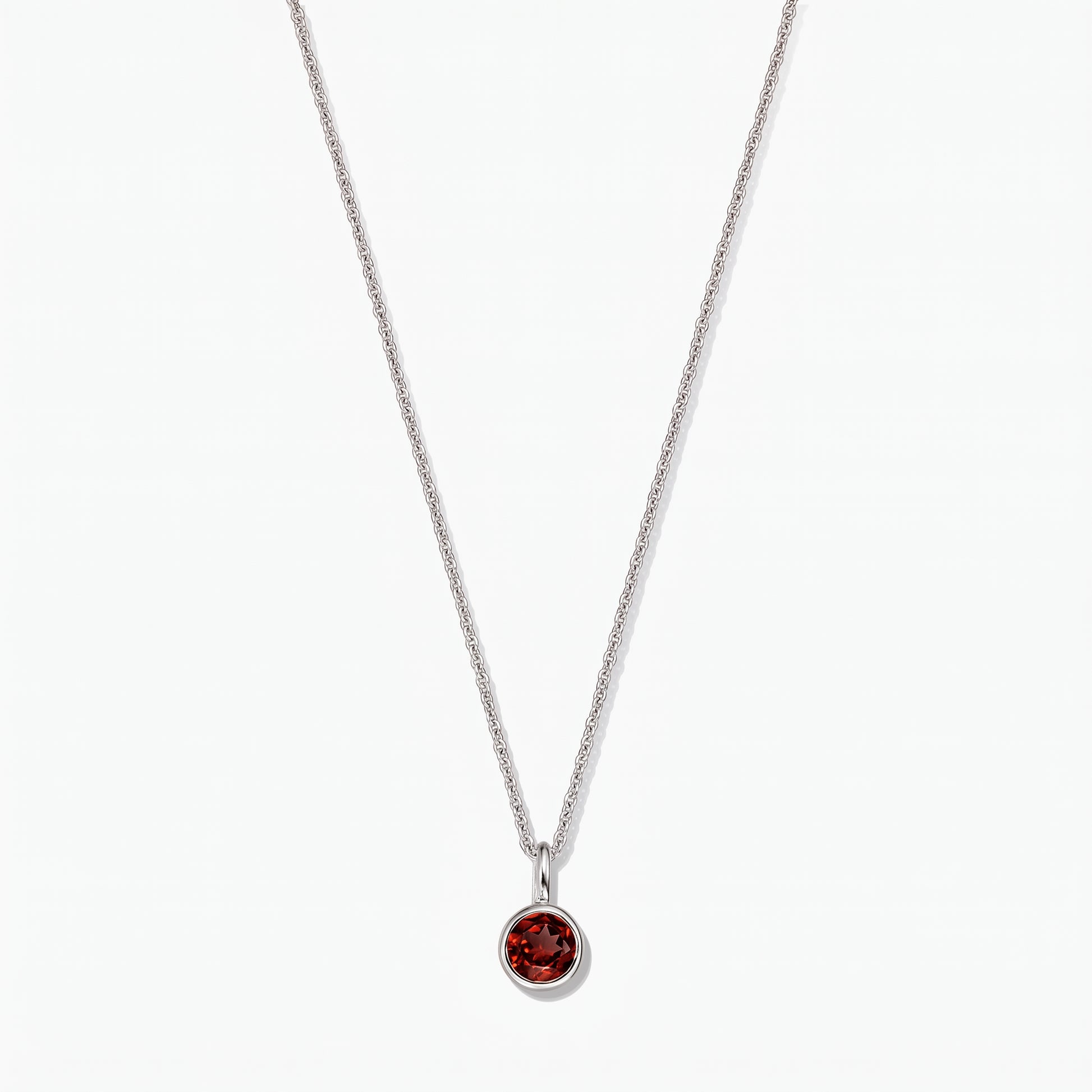Sterling silver birthstone necklace featuring a round bezel-set garnet pendant on a white background.